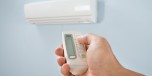 Man Adjusting Temperature Of Air Conditioner Using Remote