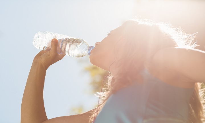 Fit blonde drinking from her water bottle on a sunny day