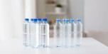 recycling, healthy eating and food storage concept - close up of plastic bottles with pure drinking water on table