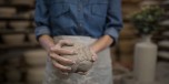 Mid section female potter holding molded clay in pottery shop