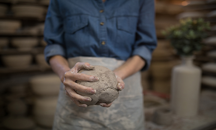 Mid section female potter holding molded clay in pottery shop