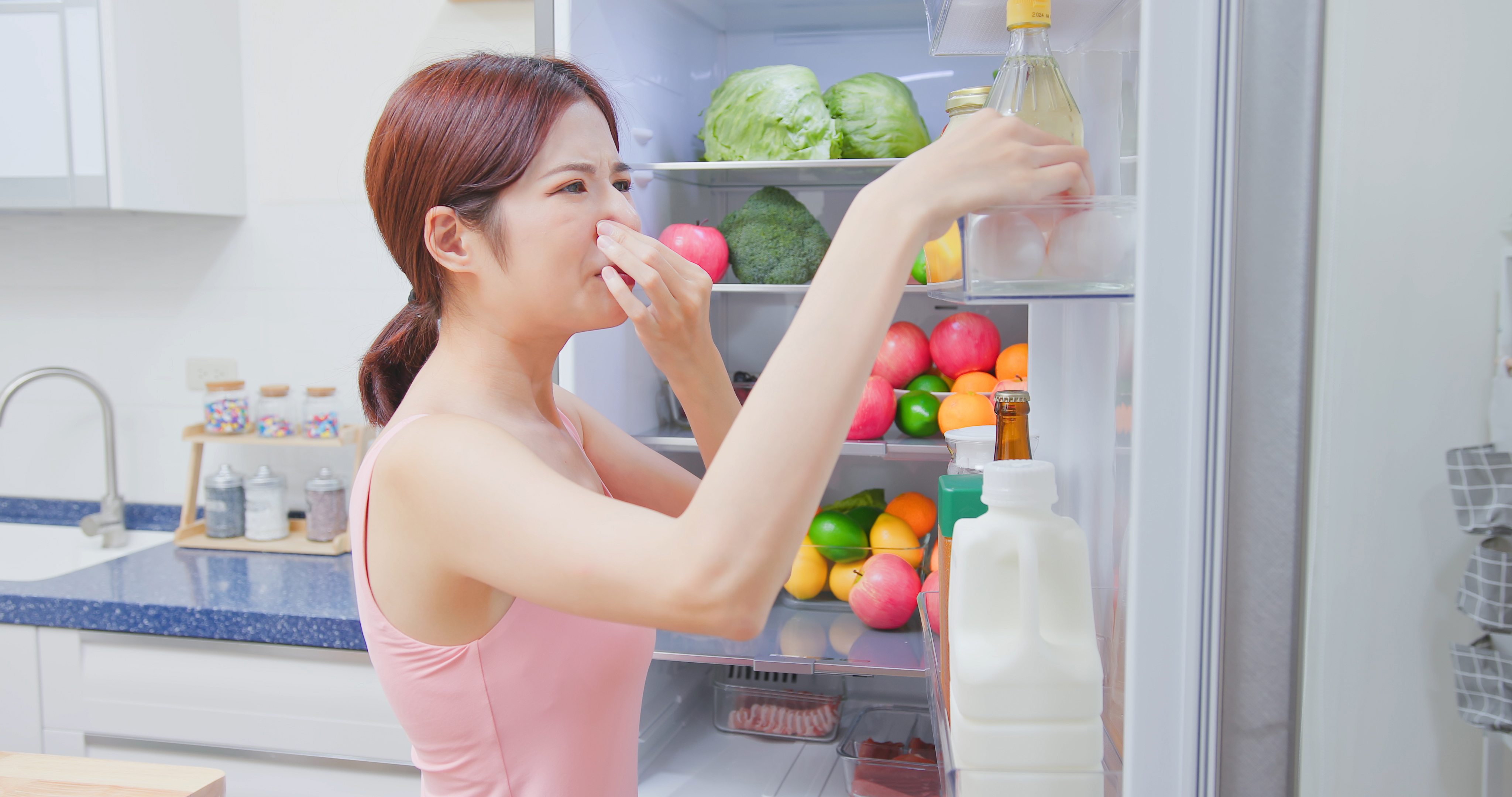 asian woman open refrigerator in kitchen and there has bad smell from food