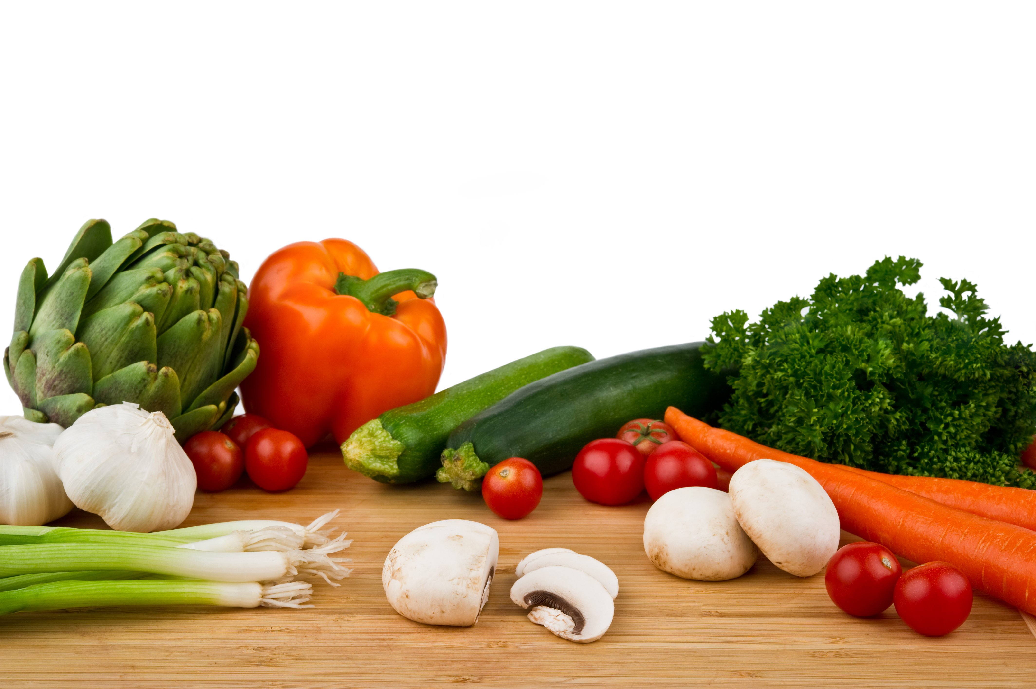 Image of a wood cutting board with assorted vegetables on a white background