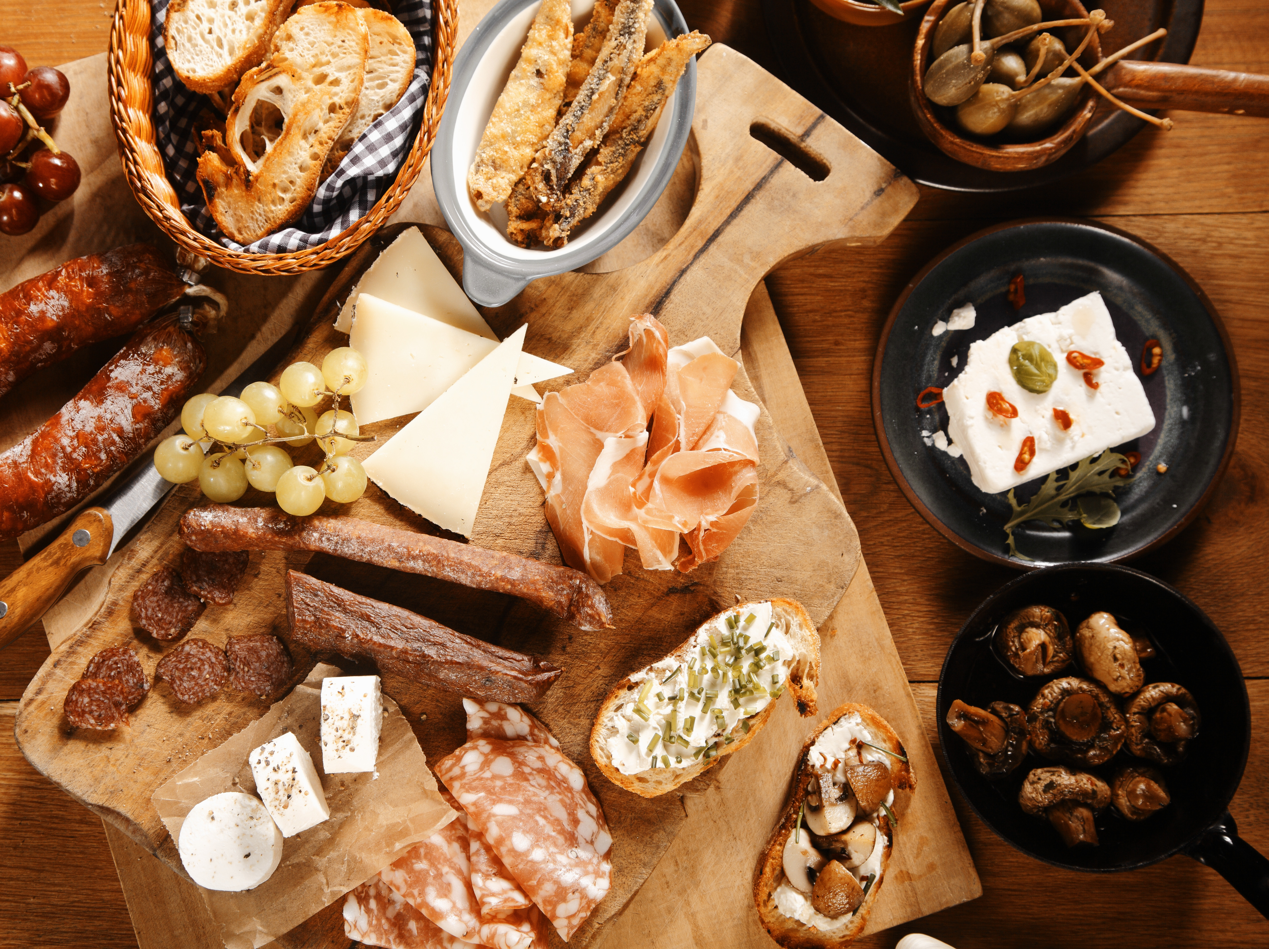 Close up High Angle Shot of Assorted Mouth Watering Tapas on Wooden Table, Emphasizing Meats, Cheese and Breads