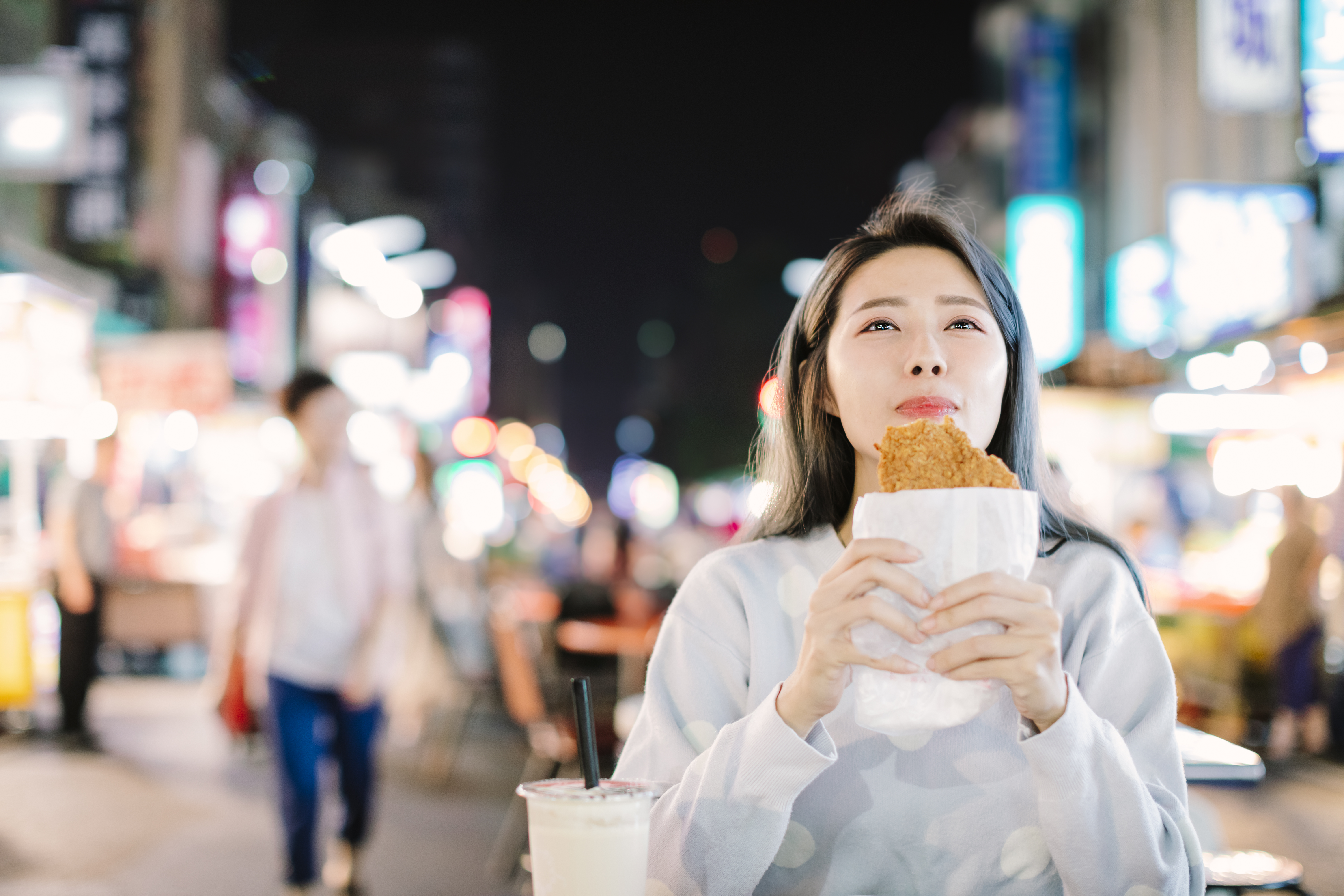 Asian woman enjoy  Chicken Fillet with street food in  Night Market