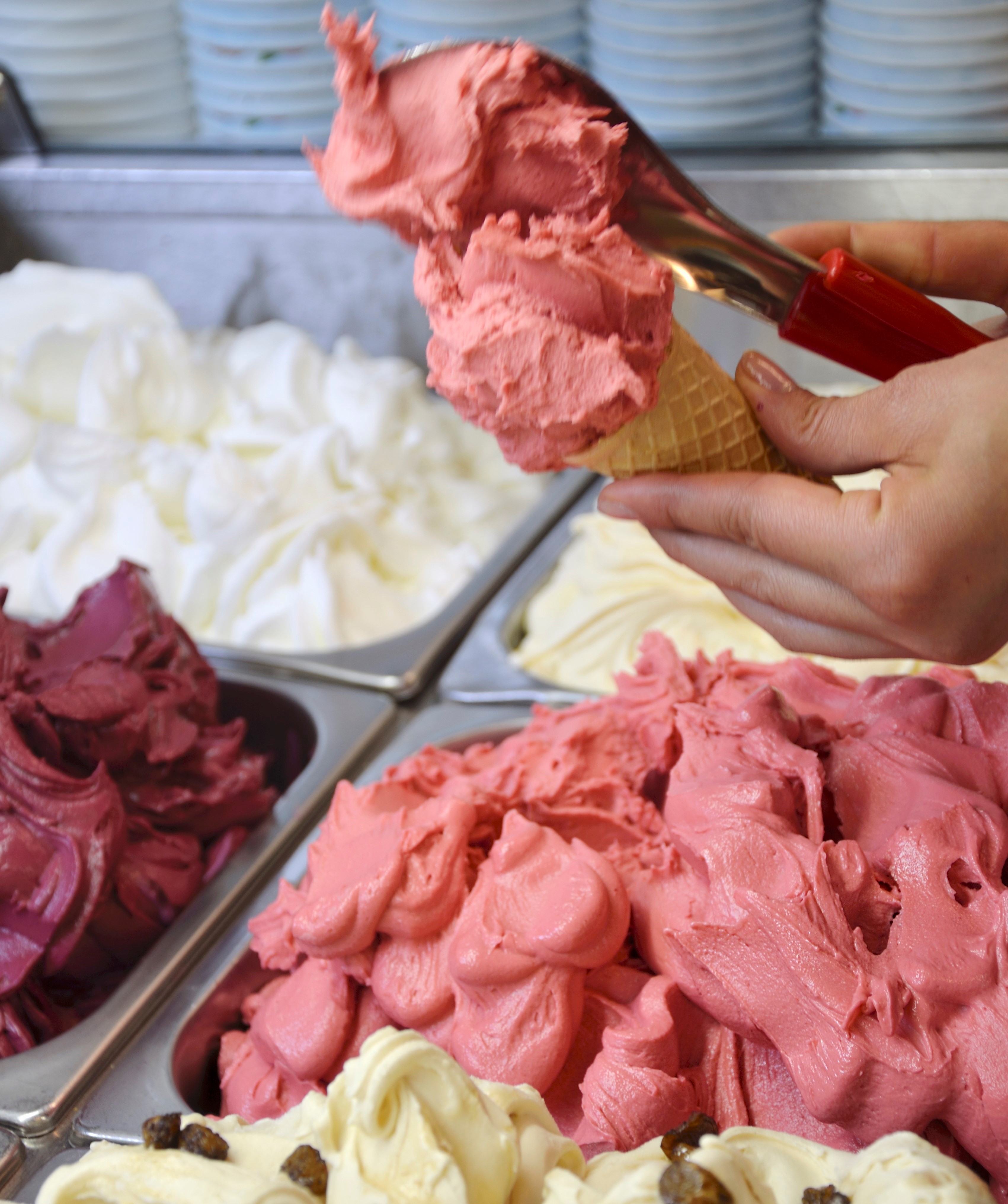 Eisverkäuferin spatelt Himbeereis in die Eiswaffel