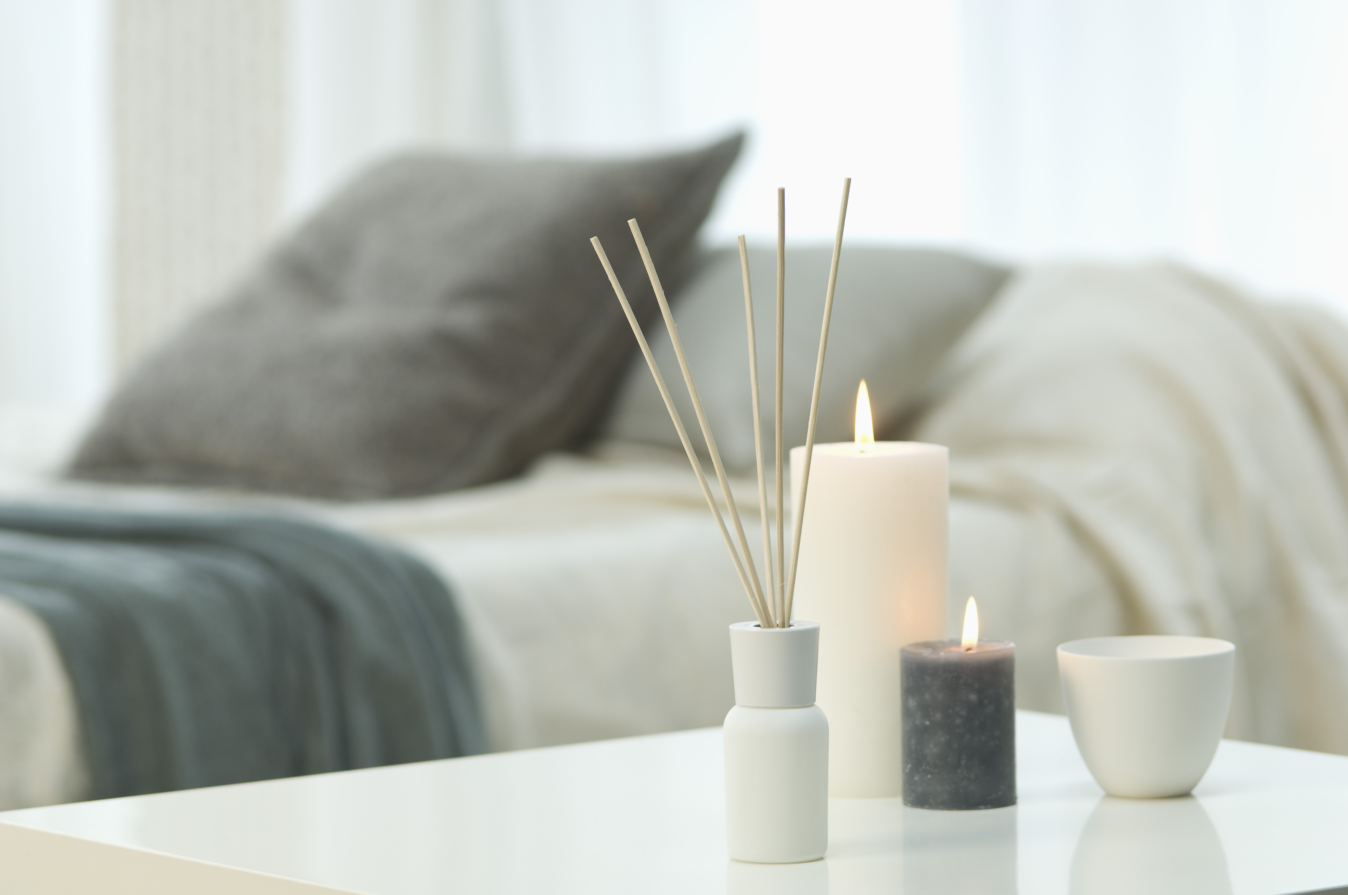 Aromatheraphy, candles and incense sticks on table with bed in background