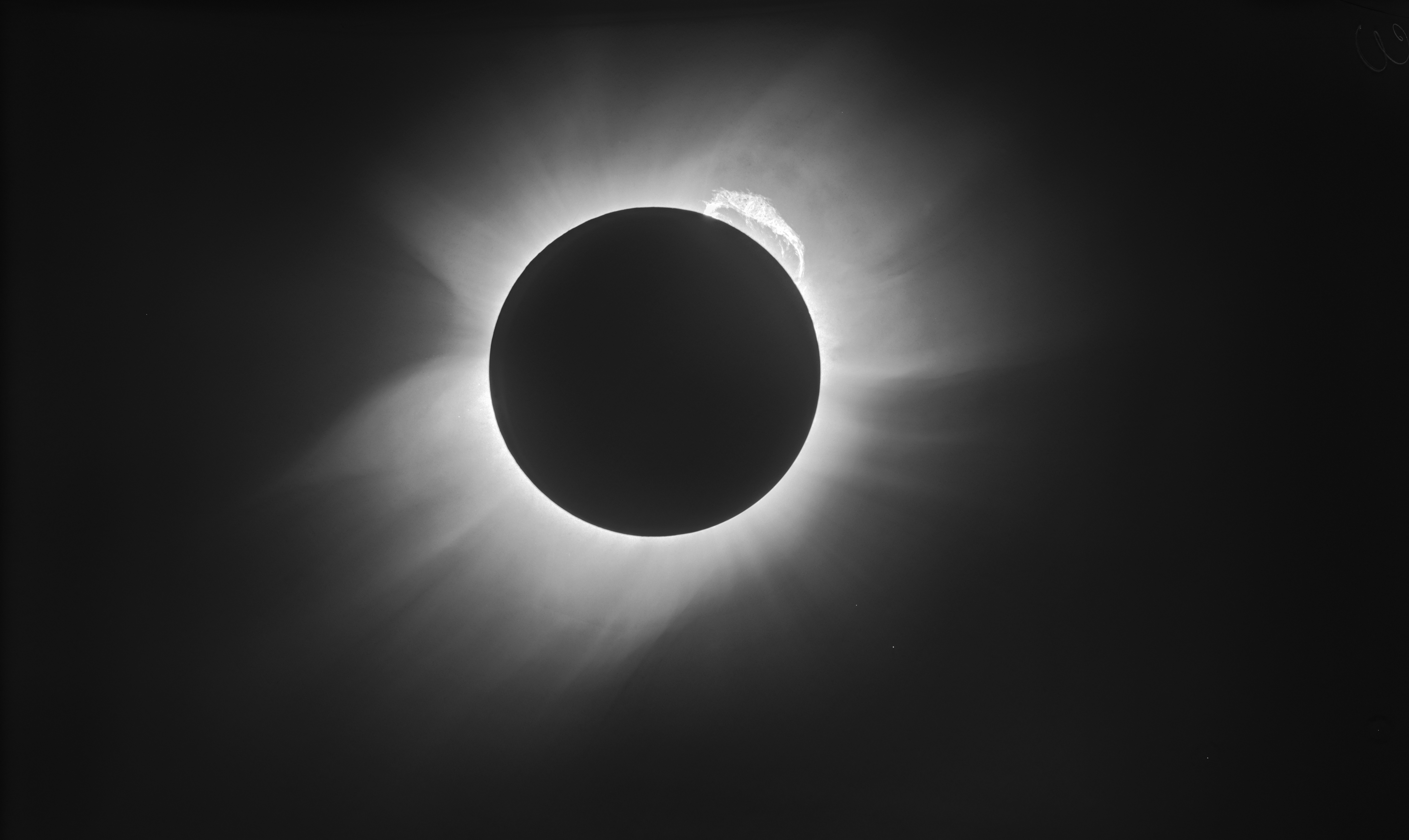 This image may not be used by or to promote the arms, nuclear power or tobacco industries or any religious organisation, or in any discriminatory way, or to imply the endorsement by ESO of any product, service or activity   1919 solar eclipse. The original image on glass photographic plate produced by the British astronomers Arthur Eddington (1882-1944) and Andrew Crommelin (1865-1939) has been processed here with modern techniques. These include image restoration, noise reduction and removal of artefacts. The image reveals details in the solar corona, a giant prominence emerging from the upper right part of the Sun, and stars in the constellation of Taurus that were used to confirm Einstein's general relativity predictions. Eddington and Crommelin travelled to locations at which the eclipse would be total, Eddington to West Africa and Crommelin to the Brazilian town of Sobral. By measuring the positions of stars during the eclipse and comparing them to their positions at night, when the sun is not in the field of view, it was possible to determine that their light rays were bent while passing close to the Sun. A key observational test of Einstein's theory of relativity.