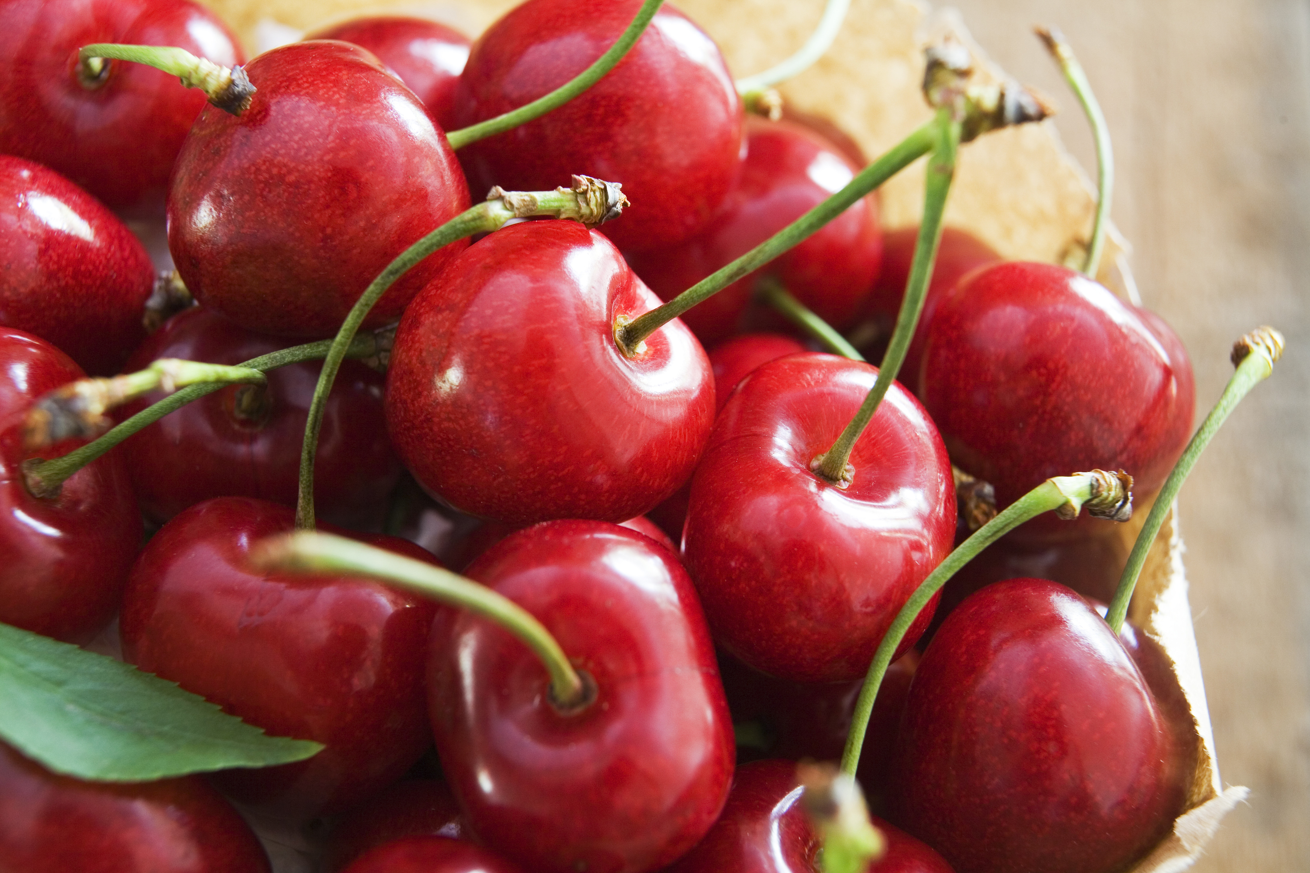 Paper bag full of red cherries on wooden background