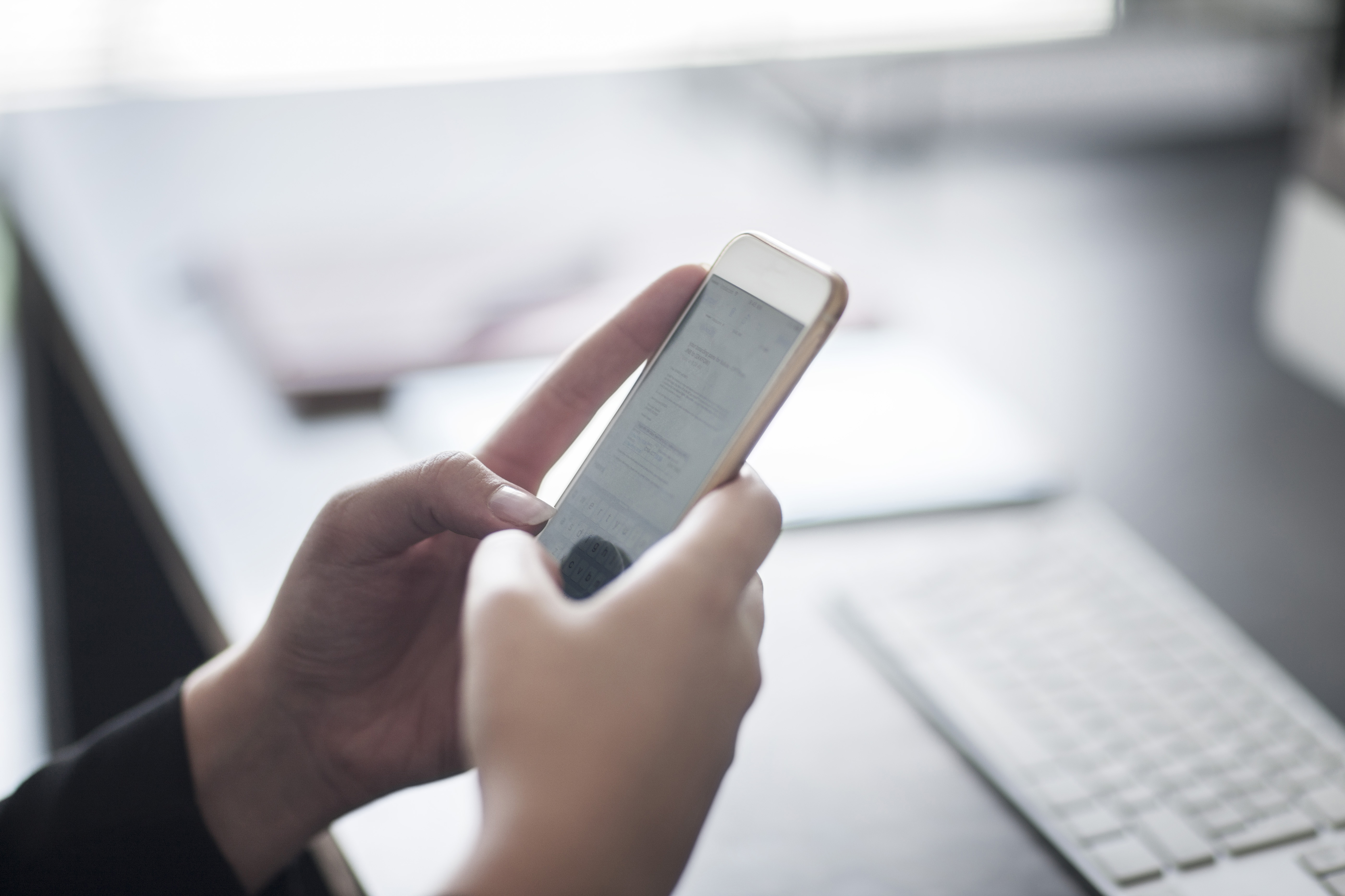 Close-up of woman holding cell phone in office