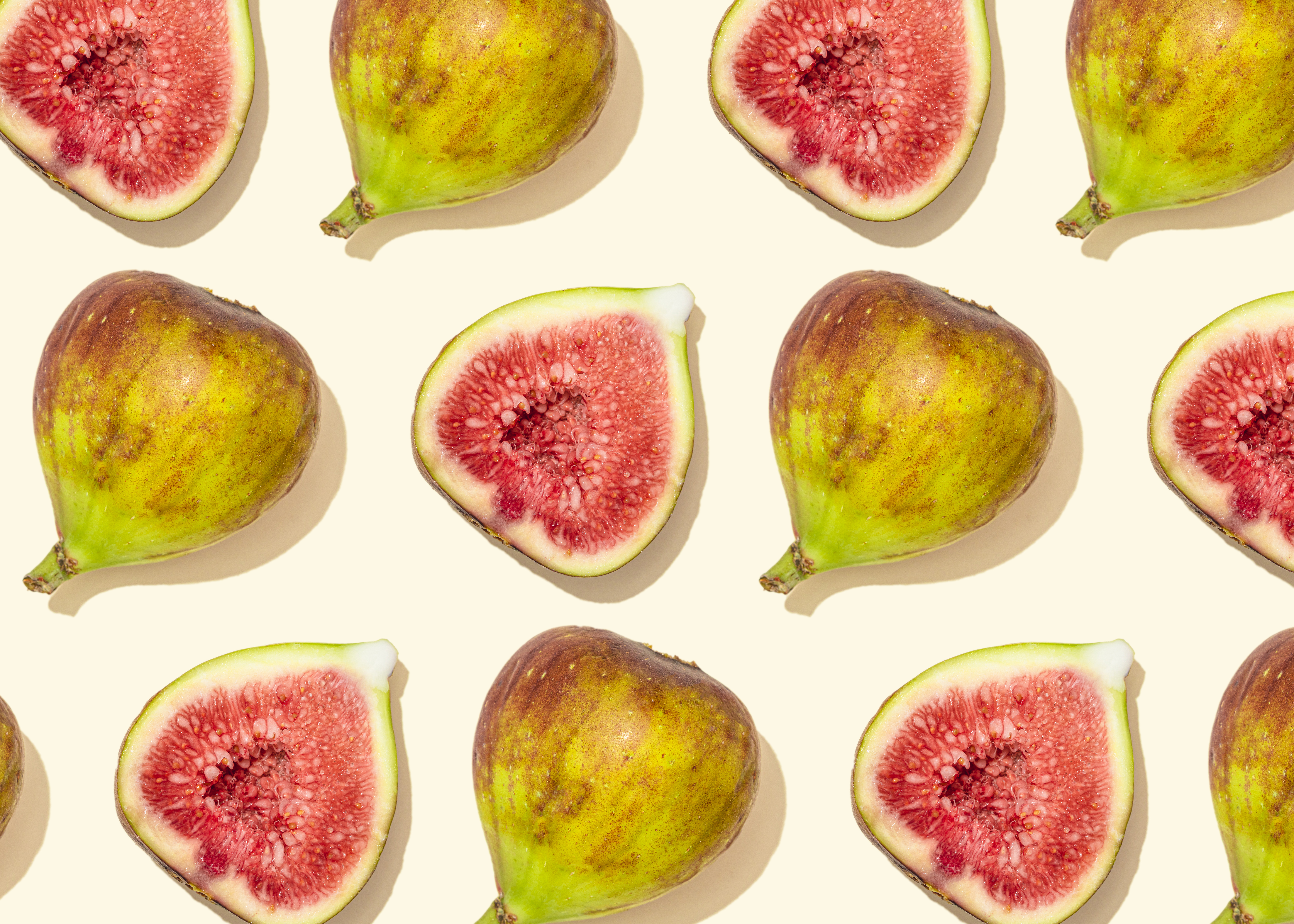 Figs on pale yellow background forming a pattern, studio shot