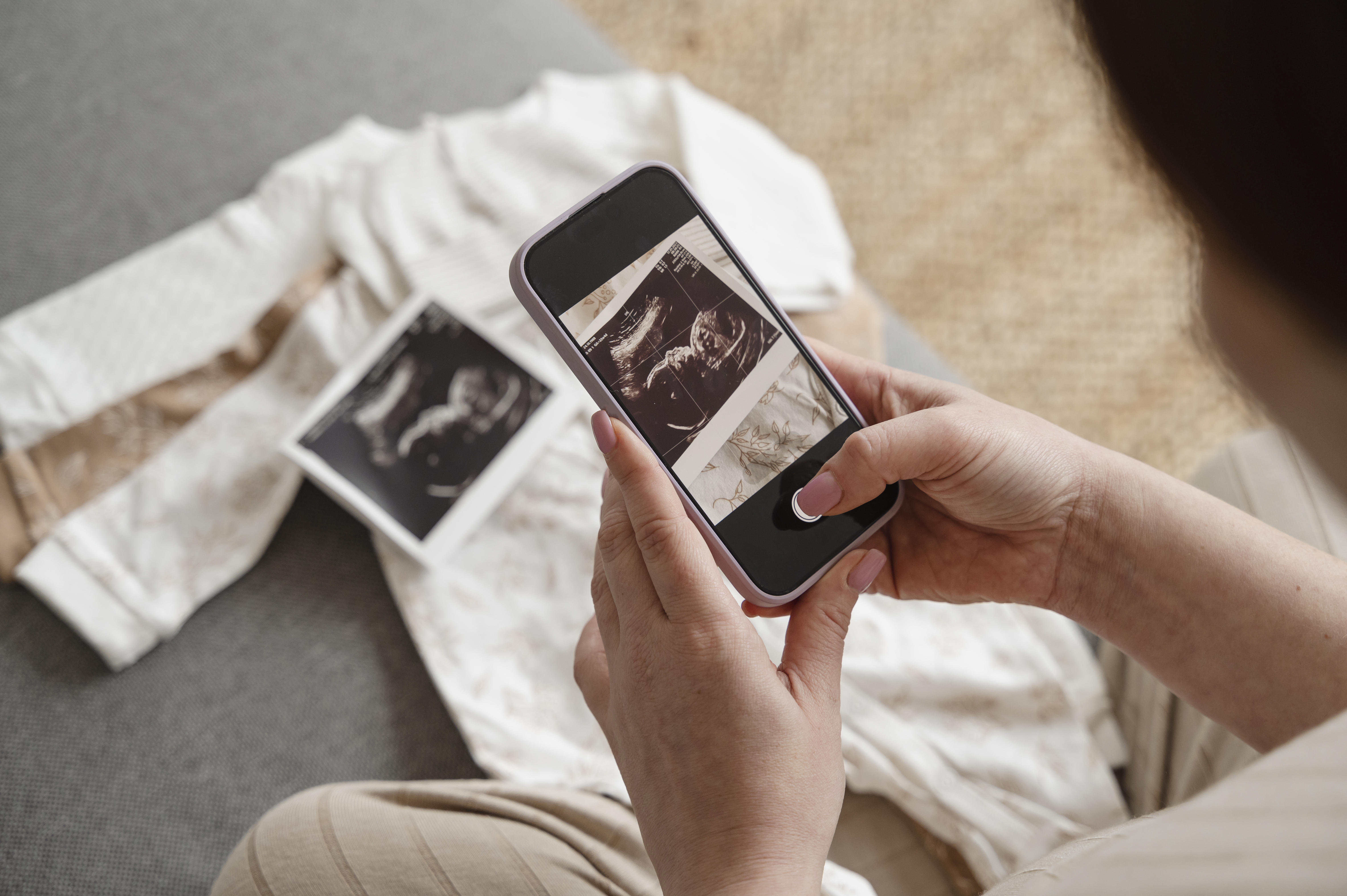 Pregnant woman taking picture of ultrasound through smart phone at home