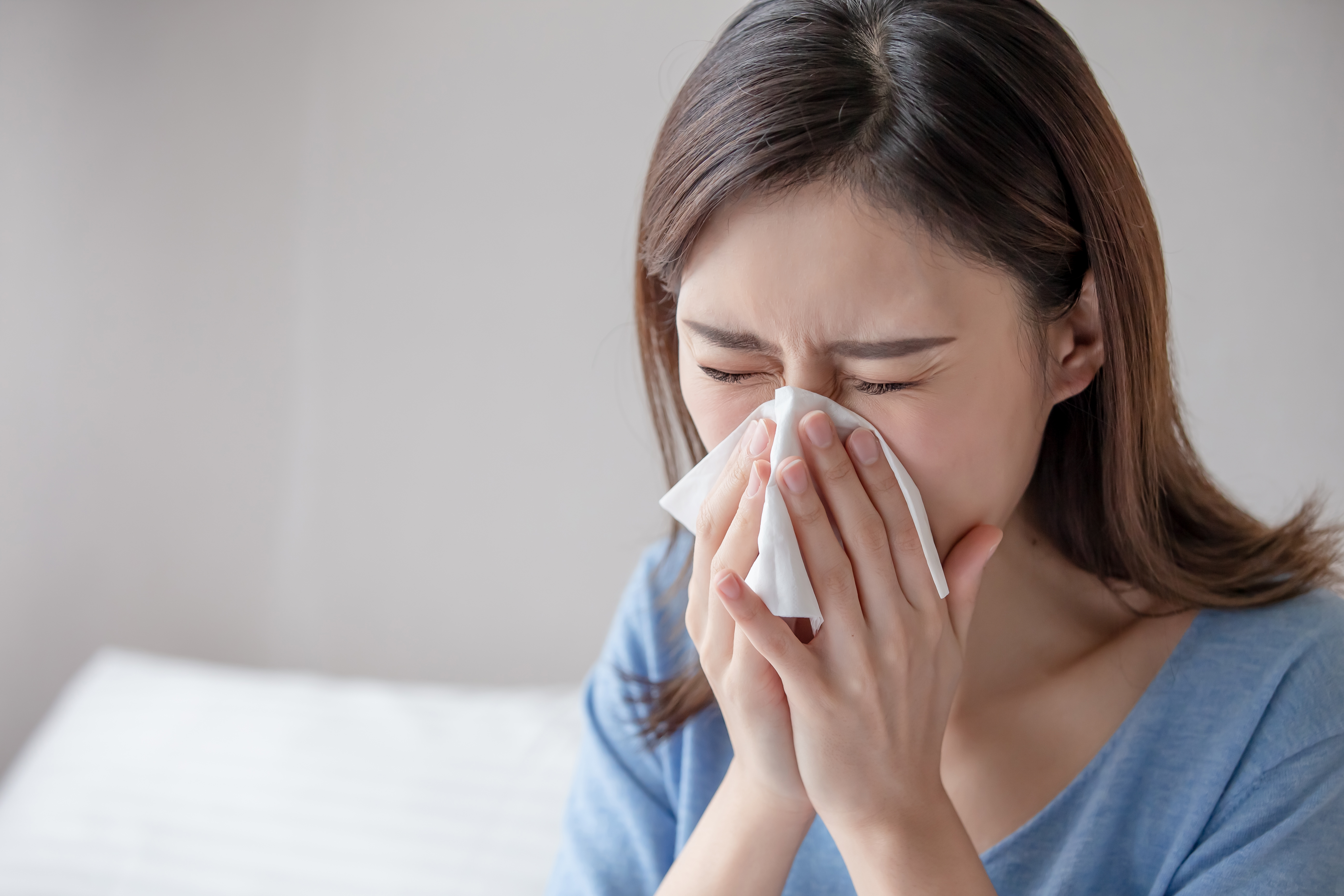 asian woman sick and sneeze with tissue paper in the bedroom