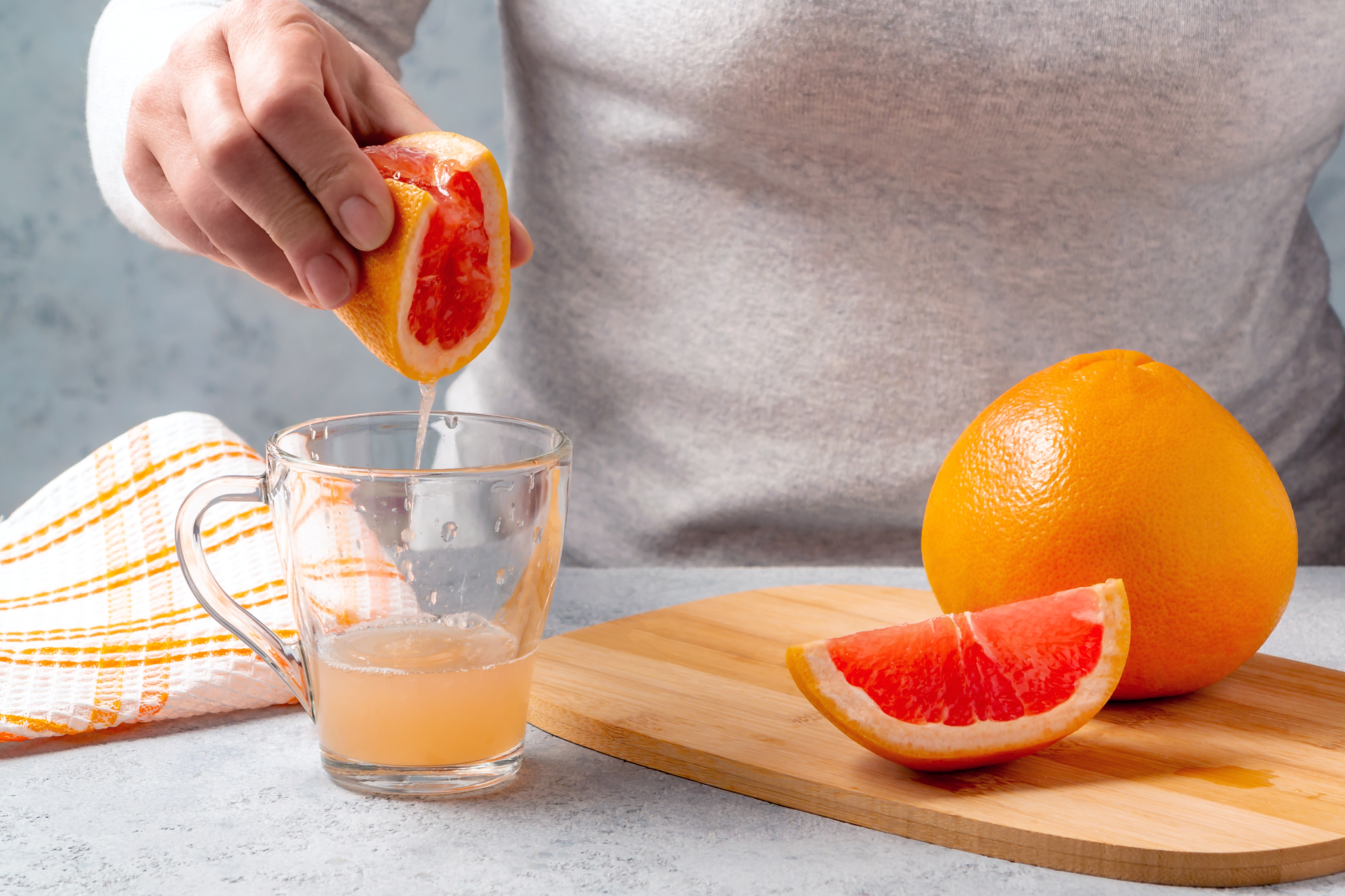 woman squeezes orange juice in a glass cup.