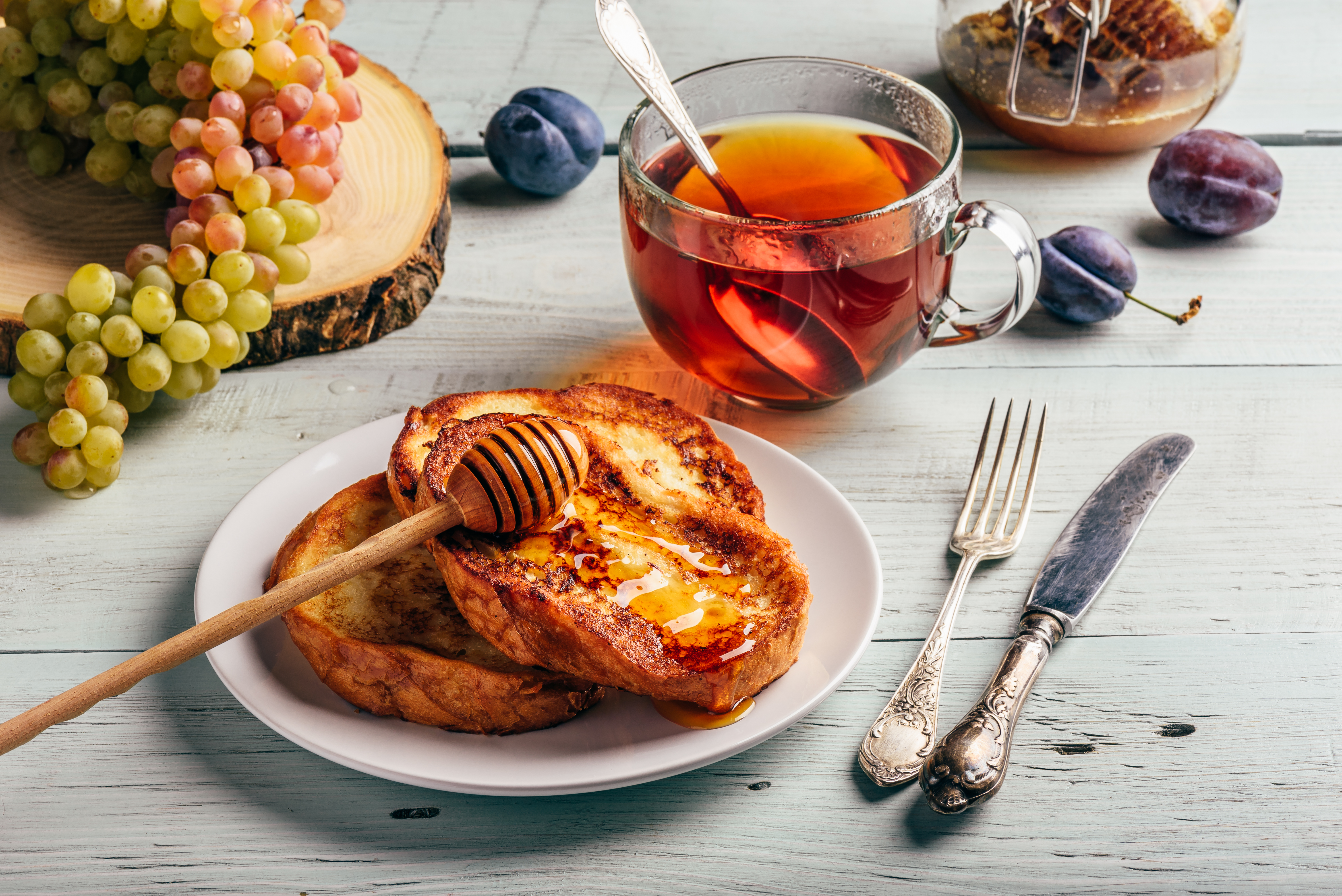 Healthy breakfast concept. French toasts with honey, fruits and tea over white wooden background