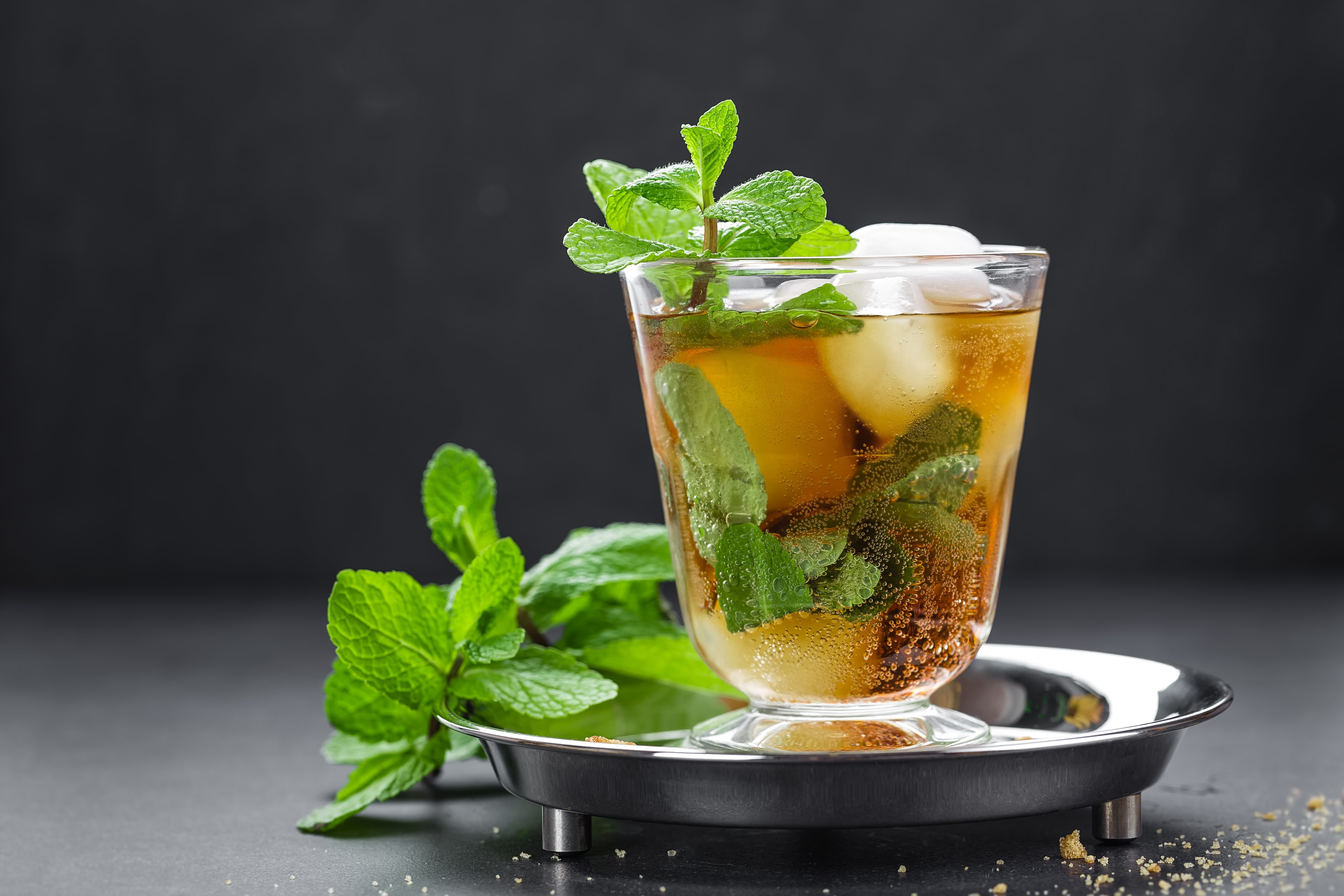 Mint Julep cocktail with bourbon, ice and mint in glass on black background