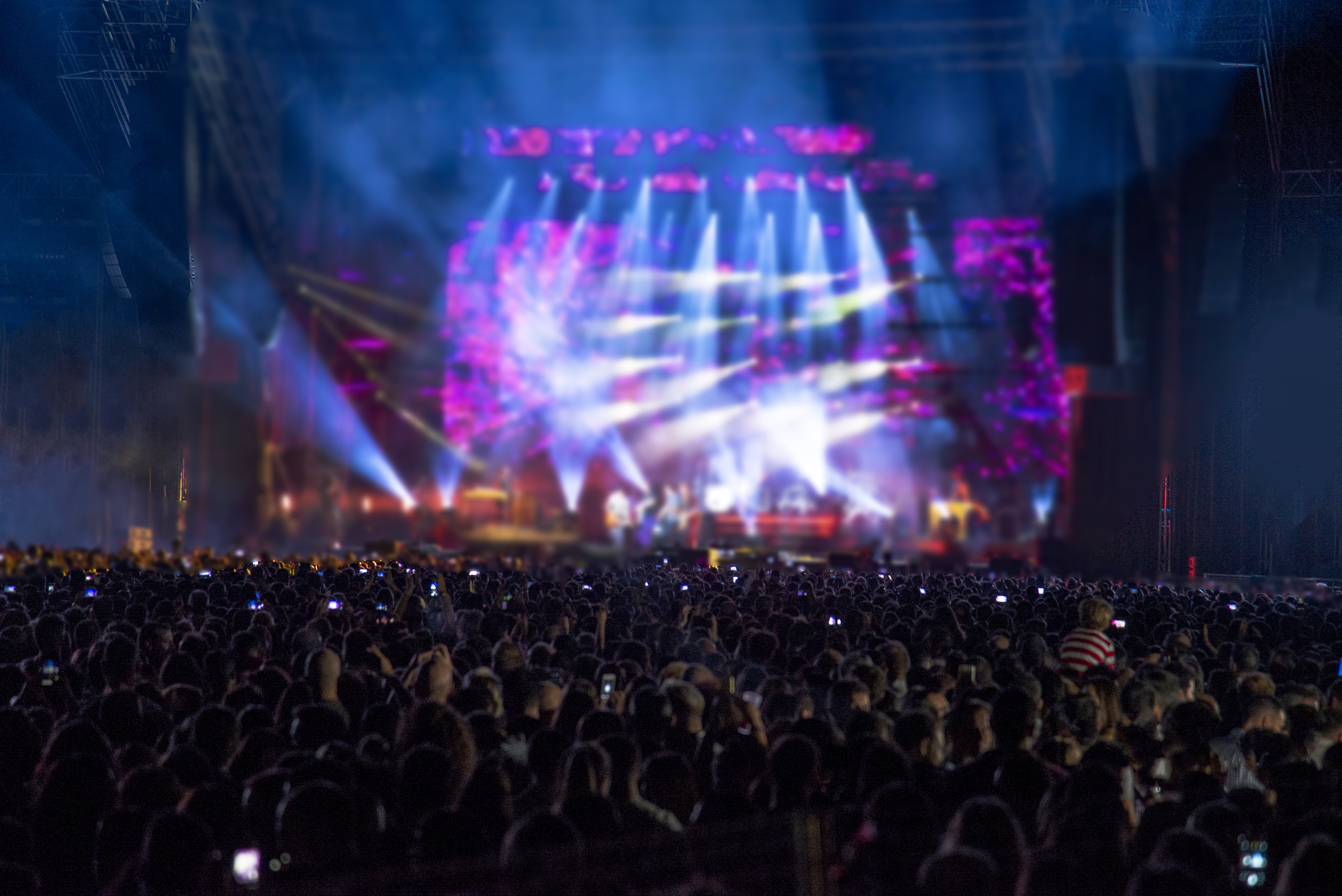 Silhouettes of concert crowd in front of bright stage lights