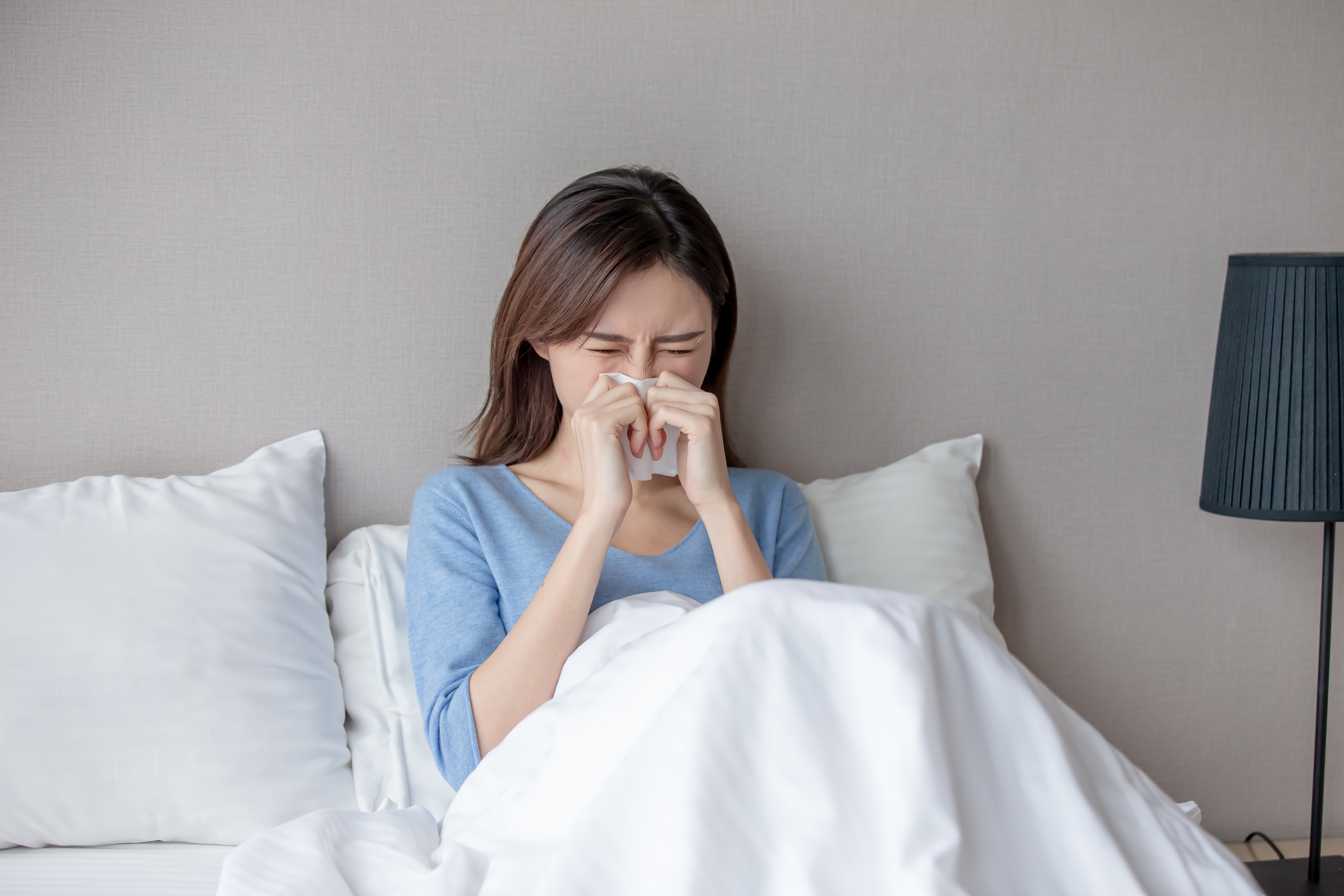 asian woman sick and sneeze with tissue paper in the bedroom