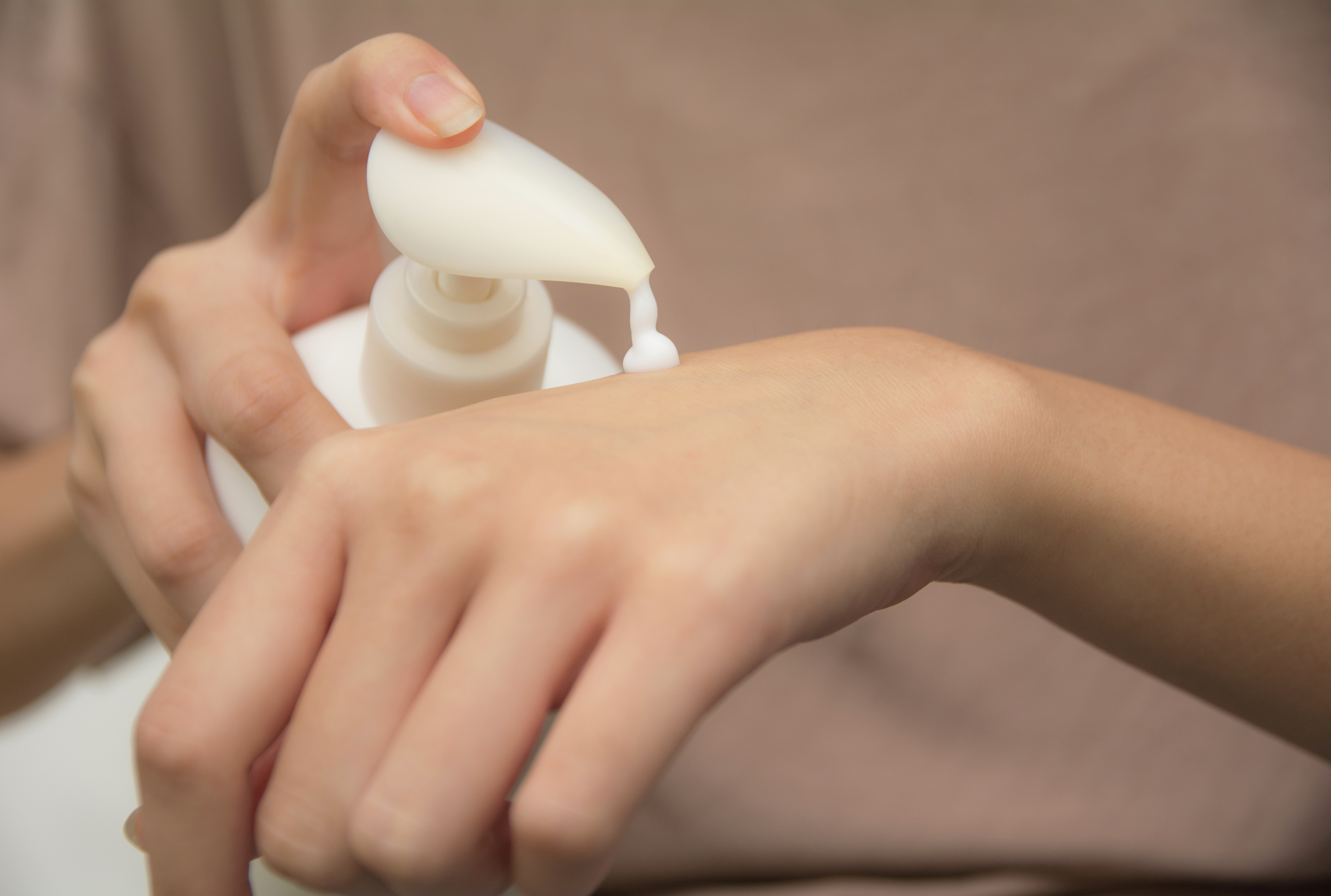 hand of woman apply lotion on skin of back hand.